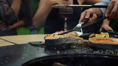 셰프가 바에 있는 bbq 그릴에서 물고기 조각을 돌리고 있다