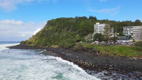 Panorama-De-Alojamientos-Frente-Al-Mar-En-La-Costa-En-Verano-Con-Olas-Blancas-Salpicando-En-La-Colina-Rocosa-De-Burleigh-En-Gold-Coast,-Queensland