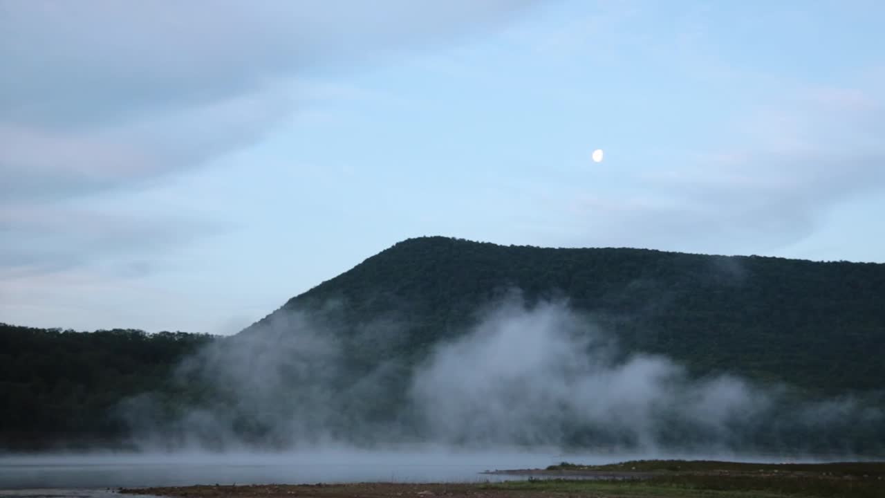 Low clouds on a lake surface with the moon in the sky