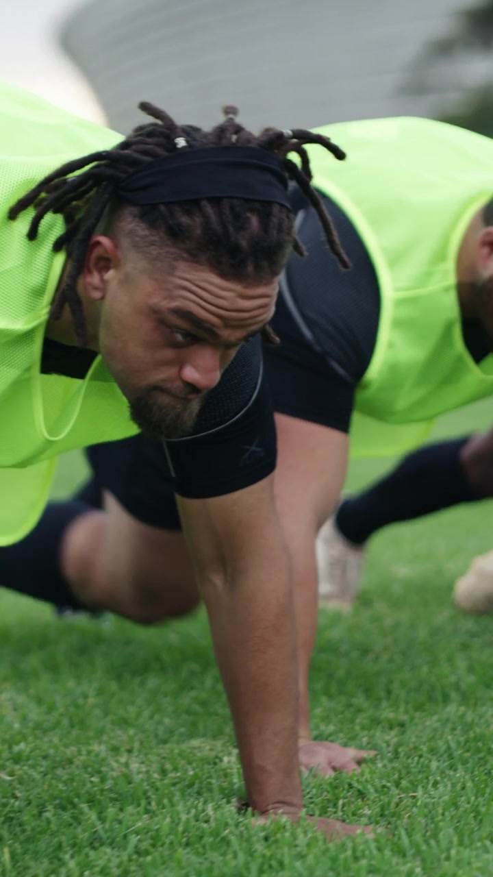 Gruppo di atleti che eseguono esercizi di bear crawl su un prato