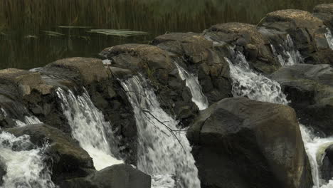 CLOSE-UP-River-Water-Flowing-Through-Stone-Weir,-SLOW-MOTION