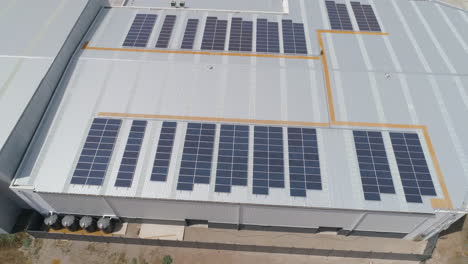 Aerial-close-up-rising-to-reveal-solar-panel-package-installation-on-warehouse-rooftop