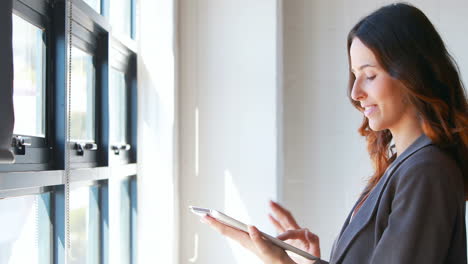 Mujer-De-Negocios-Usando-Su-Tableta-Junto-A-La-Ventana