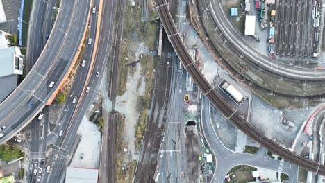 Top down shot from above Brisbane City&#039;s Mayne Railway Yard, as a train passes through the shot, Busy car traffic on road leading to ICB inner city bypass