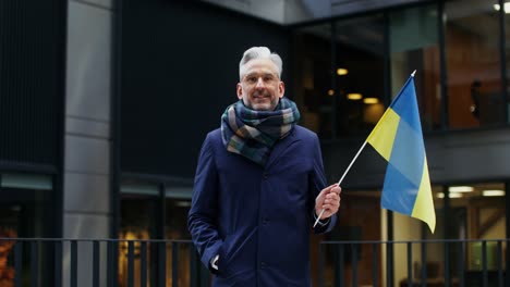 man holding ukrainian flag in city