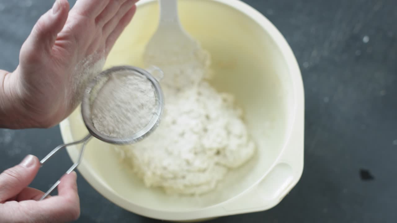 Female hands sifts the flour