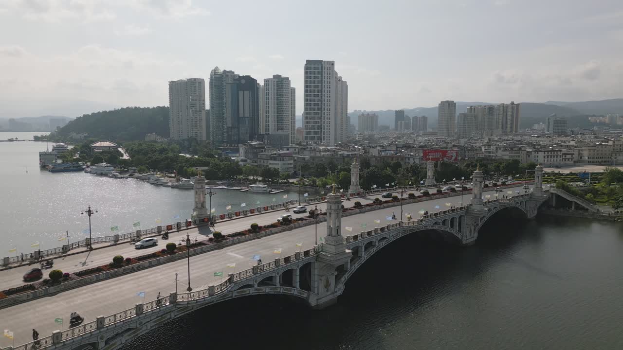 Upward panning drone footage of traffic along Xing Sheng Bridge in Dali City, Yunnan, China