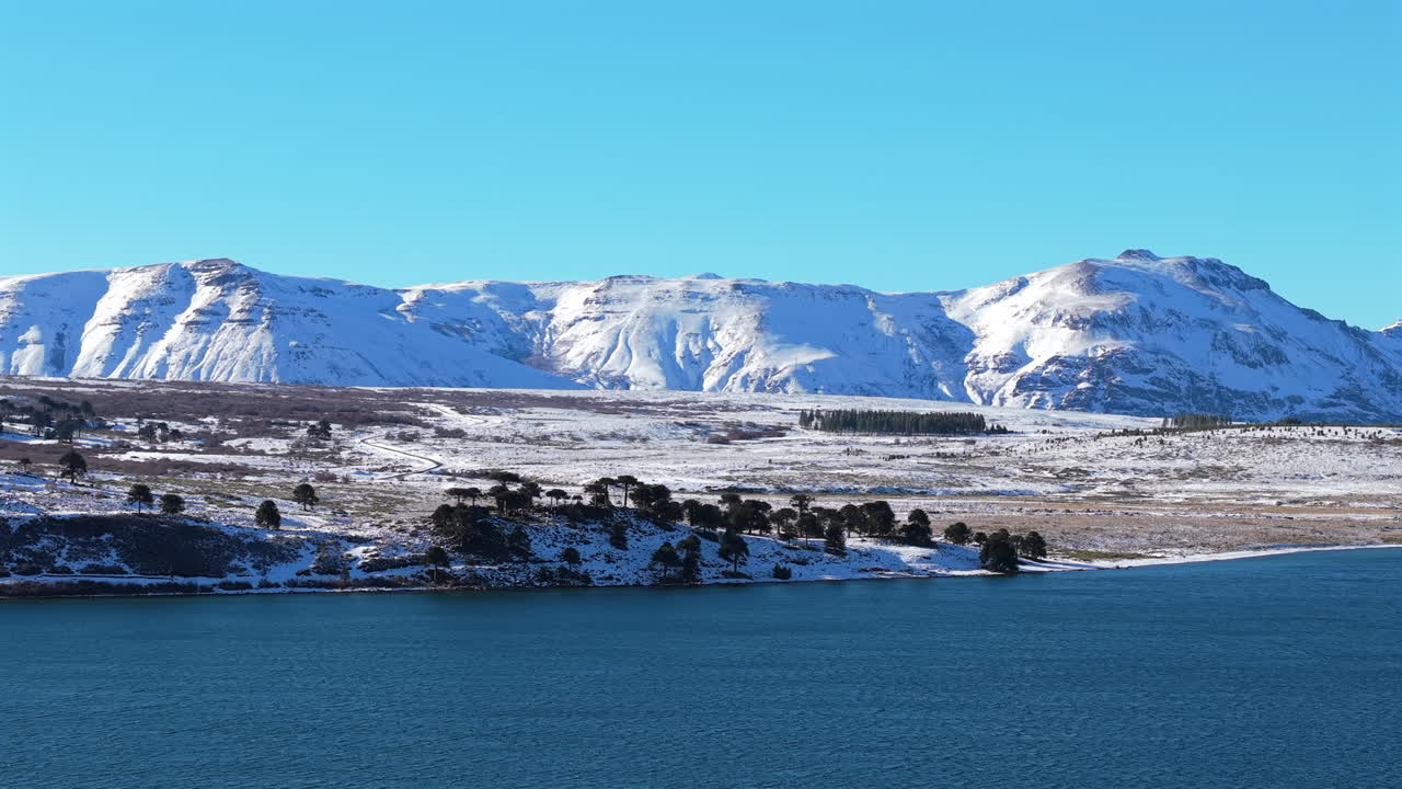 Aerial view of Patagonia’s Caviahue Lake, surrounded by snowy landscapes and serene wilderness