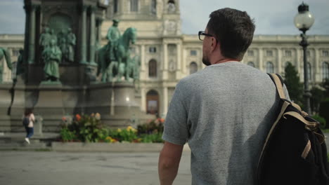 man walking by monument in a city square