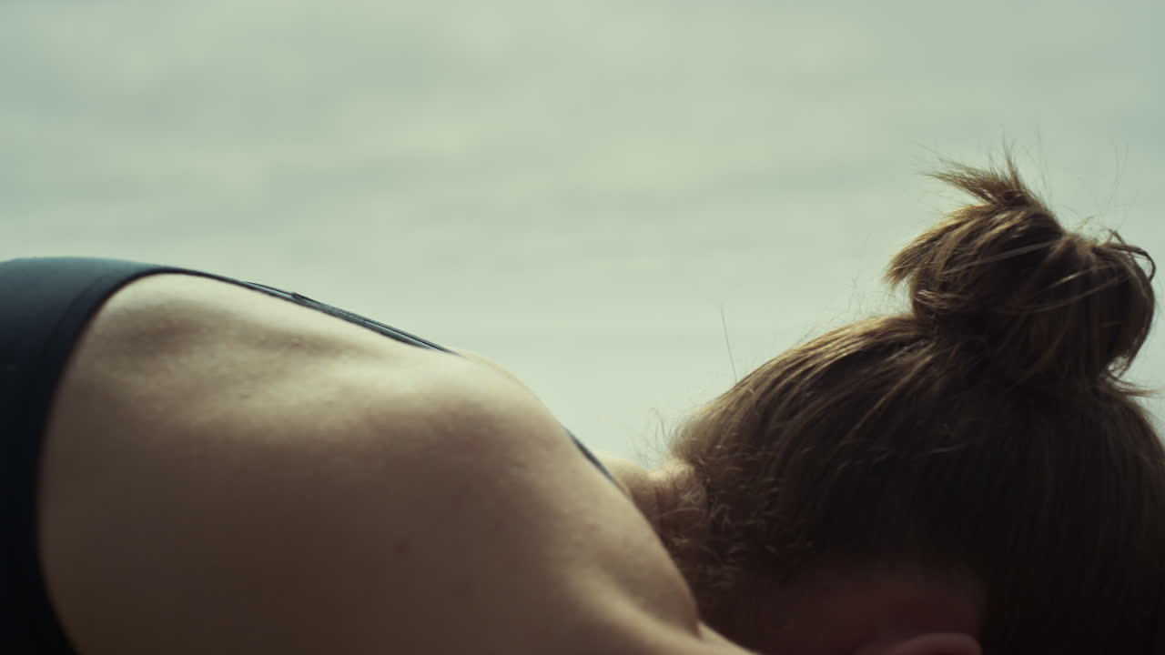 Nærbillede af kvinde, der bøjer ryggen og praktiserer yoga på stranden. Pige i strækstilling.
