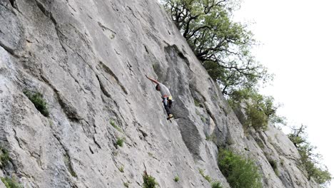 Male-climber-ascending-on-cliff-in-summer