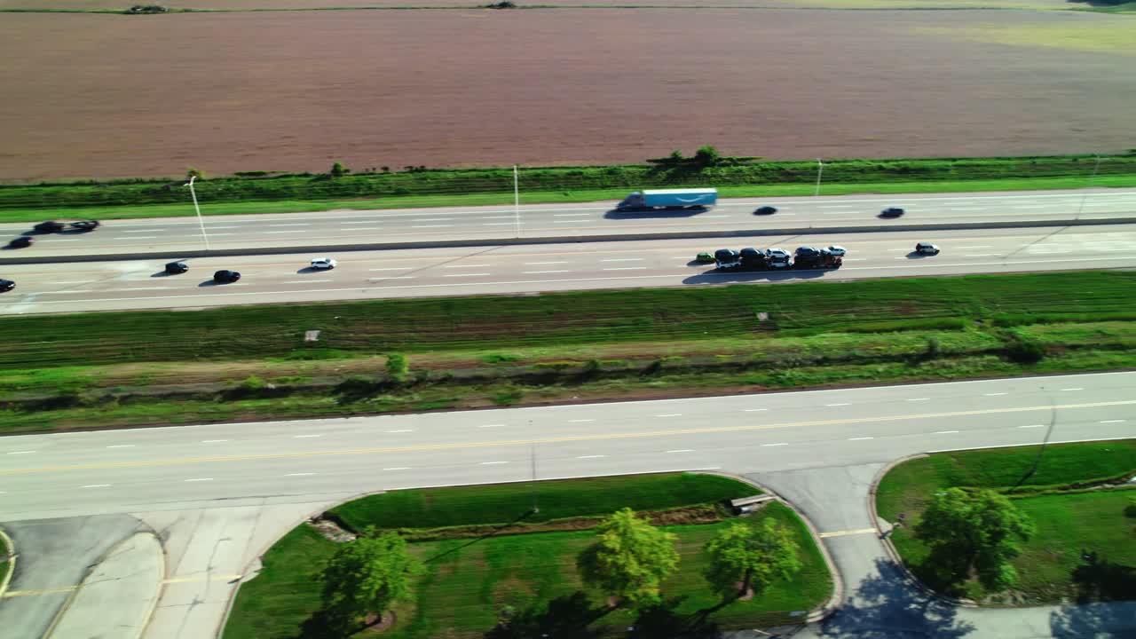 Ripresa aerea in movimento di un camion bisarca che viaggia sull'autostrada carico di automobili.