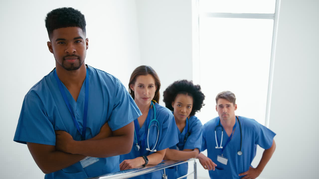 Portrait Of Serious Multi Cultural Medical Team Wearing Scrubs Standing On Stairs In Hospital