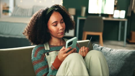 Woman using phone and credit card on couch