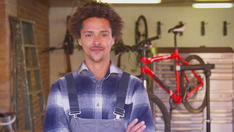 portrait of man in garage at home with cycle hanging on wall behind