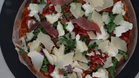 vista aérea de la pizza italiana con tomates, queso feta, prosciutto y rúcula. vista de arriba hacia abajo de la pizza con ingredientes gourmet