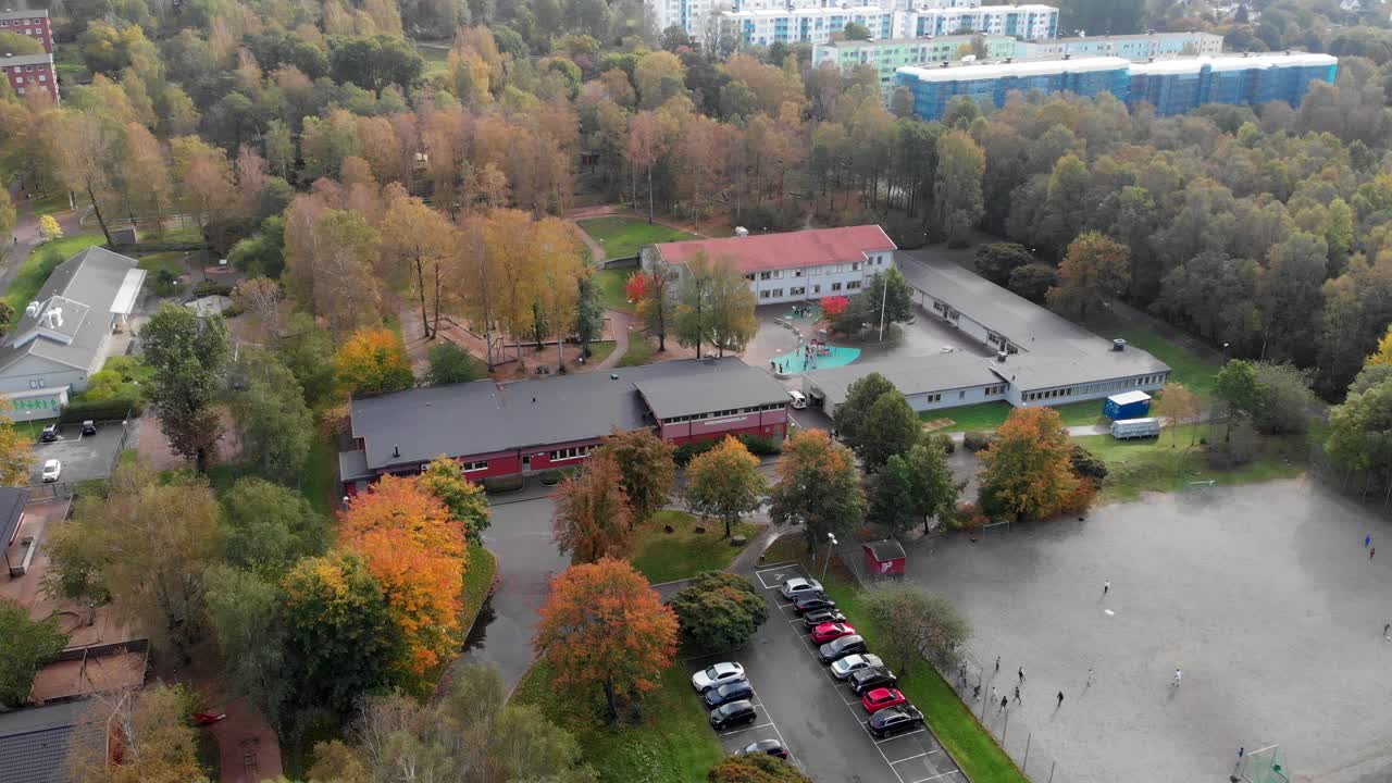 аэрофотосъемка, детский сад-школа в окружении деревьев, дети играют в футбол на поле