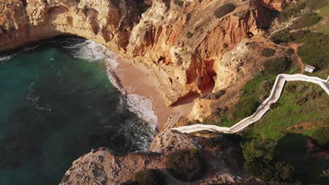 Un-Dron-Aéreo-Disparó-Sobre-Una-Hermosa-Playa-En-Forma-De-Herradura-Con-Escaleras-Blancas-Que-Conducen-A-La-Playa-Sobre-Un-Acantilado-Alto