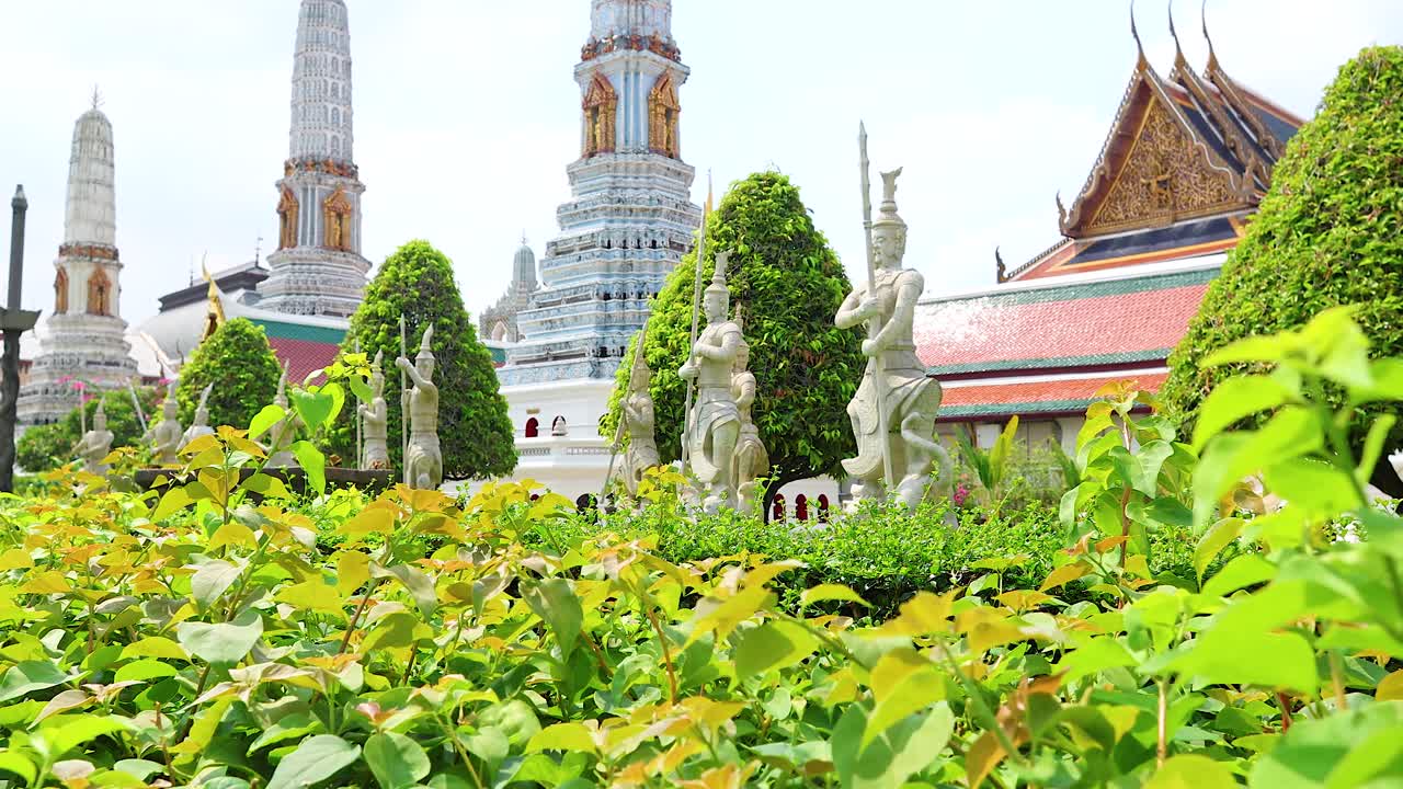 A tranquil scene of Wat Phra Kaew in Bangkok, showcasing lush greenery and ornate architecture under bright daylight