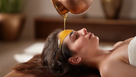 Woman receives traditional Shirodhara Ayurvedic oil treatment