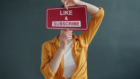 woman holding a sign that says 'like & subscribe'