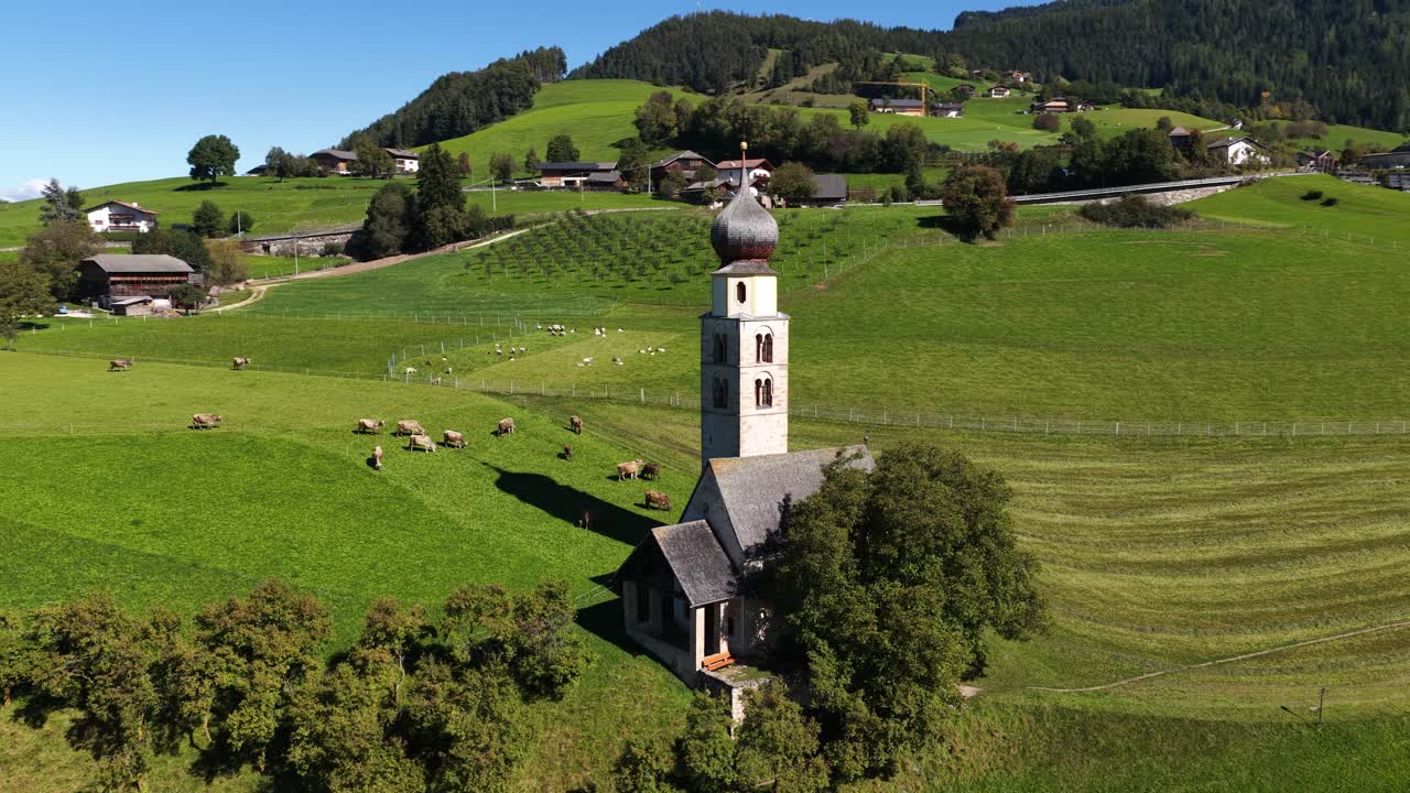 Small church, chiesa in the Italian dolomites. Alpine fields, agricultural grass lands. Aerial video