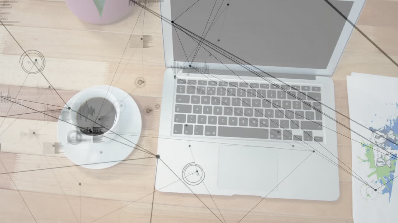 Silver laptop computer showing network data flowing across wooden desk, with coffee and plant