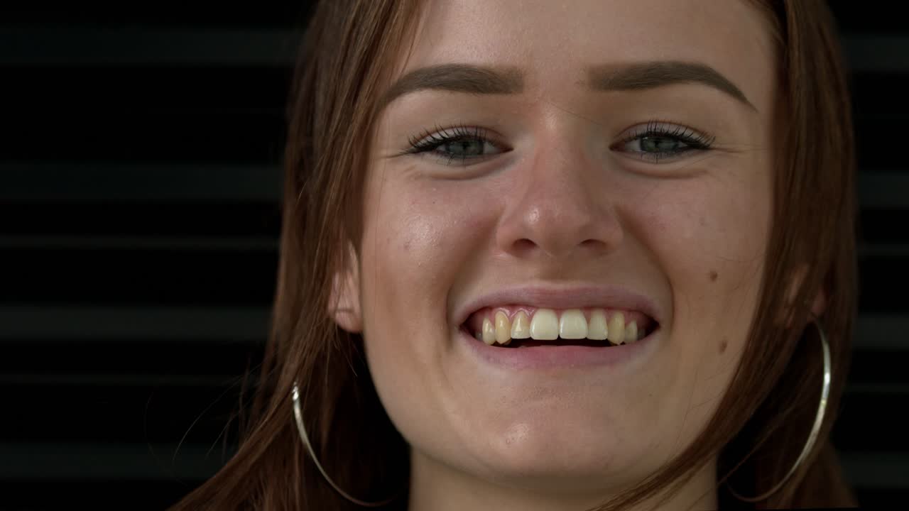 primer plano retrato joven mujer morena sonríe y mira directamente a la cámara en el estudio de fondo negro de cámara lenta