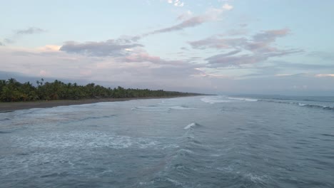 Bird's-eye-view-rising-over-the-beach-and-the-white-foaming-waves-of-the-Pacific-surf