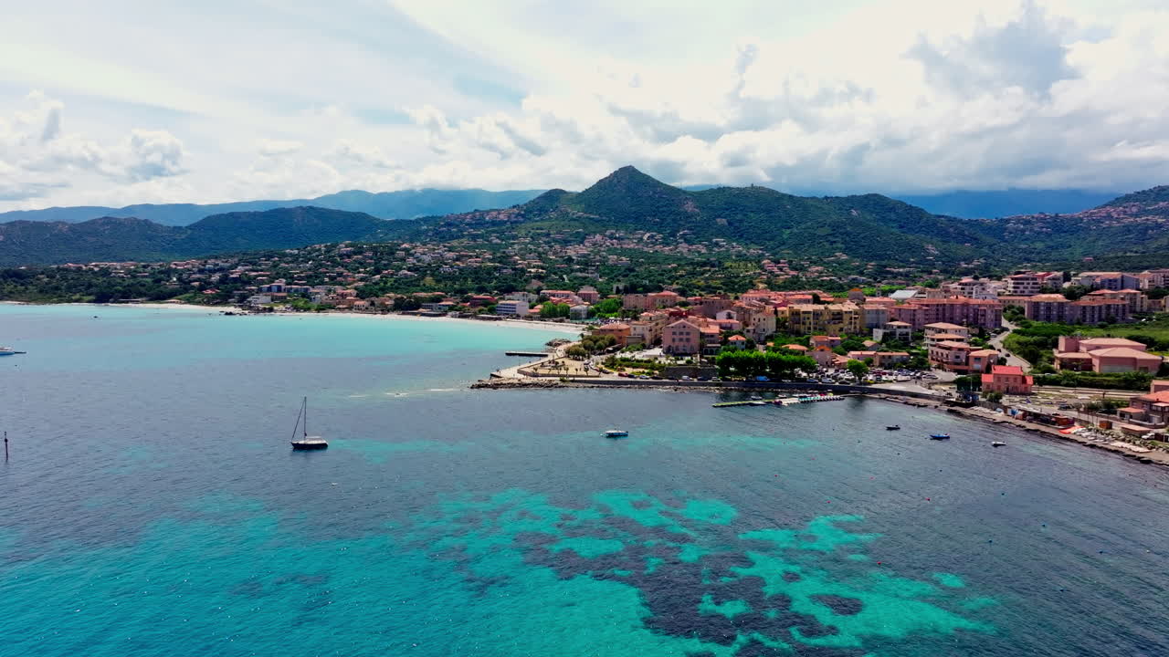 Aerial drone shot over the coastal town Île-Rousse in the Balagne region in Corsica, France. View of harbor and the docked boats