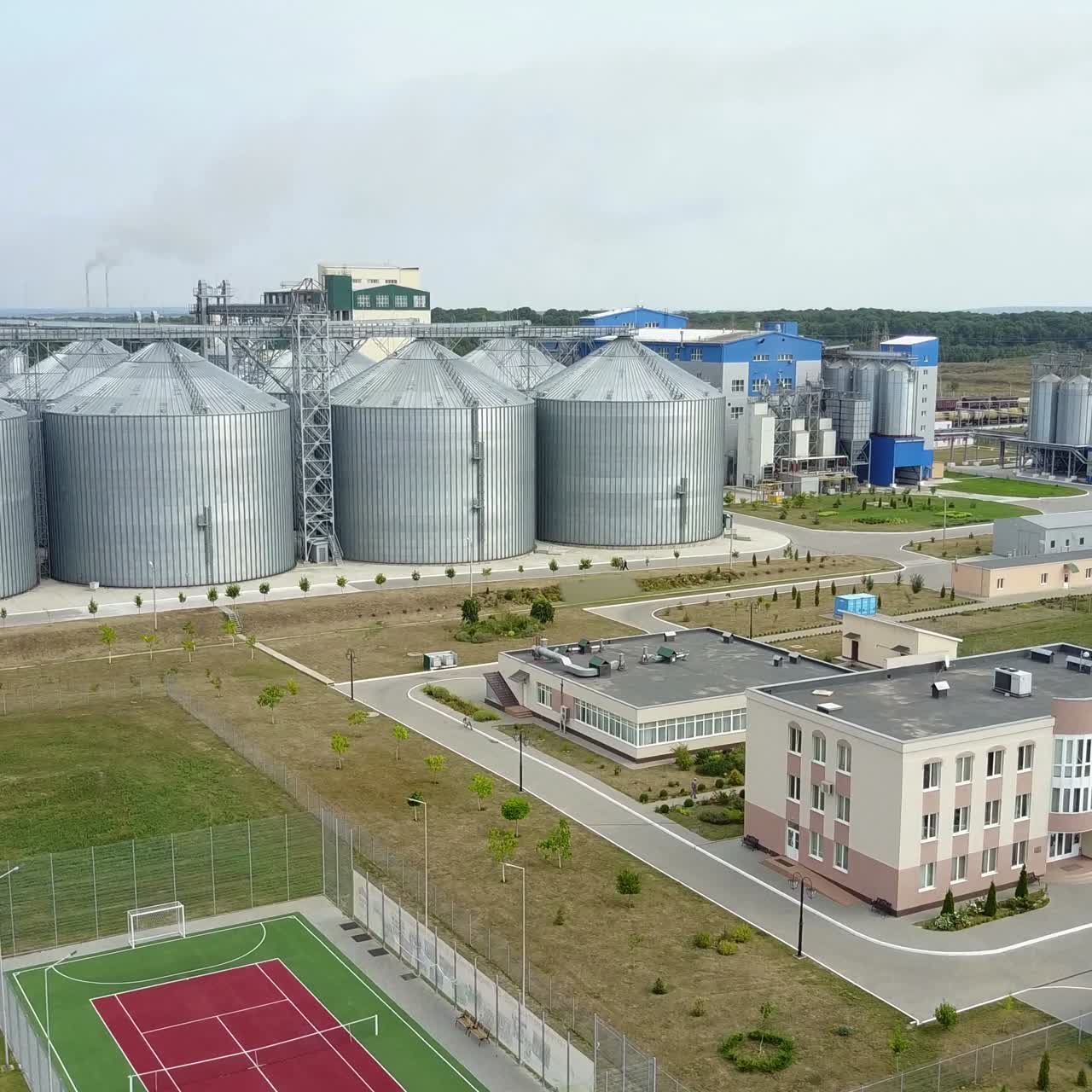 Aerial view of grain elevators surrounded by green fields.