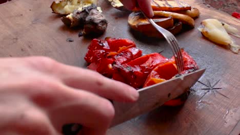 Cutting-roasted-red-pepper,-with-roasted-vegetables-in-background