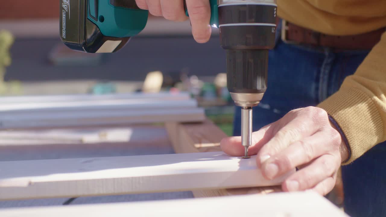L'artigiano tiene la vite in mano e la avvita nel legno.