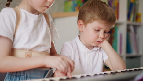 schoolgirl comforts upset little brother during piano lesson