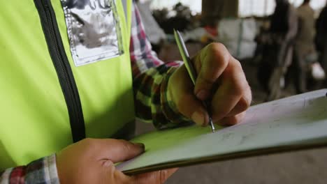 Male-worker-writing-on-clipboard-in-warehouse-4k