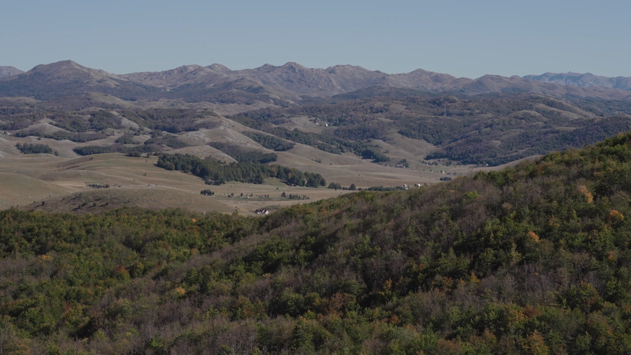 Forested hills with layered valleys and rugged mountains at Durmitor National Park, Montenegro. Static camera view