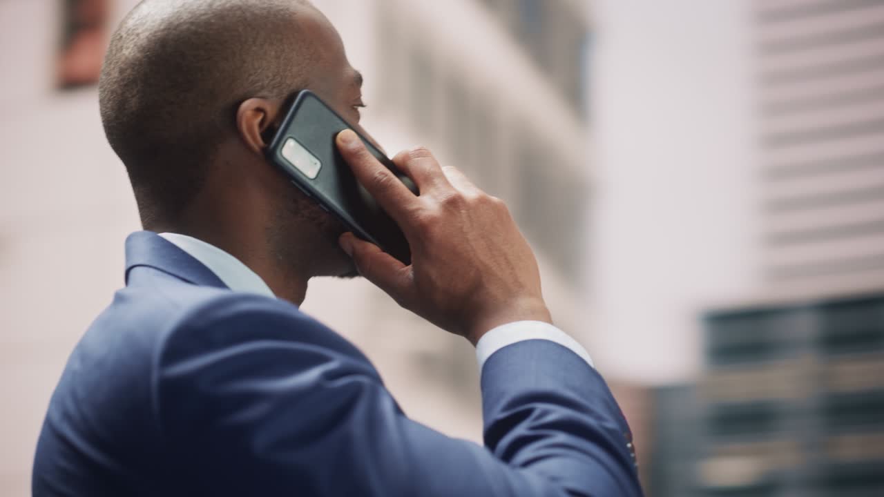 360 Degree Street Shot: Portrait of Confident Black Businessman Talking on Smartphone in City. Successful African American Entrepreneur Using Mobile to Make a Phone Call. Tracking Moving Around Shot
