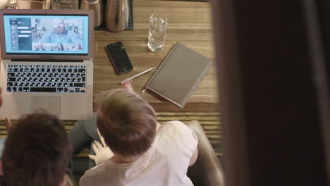 top view of coworkers sitting at a table in an online meeting with a red haired businessman