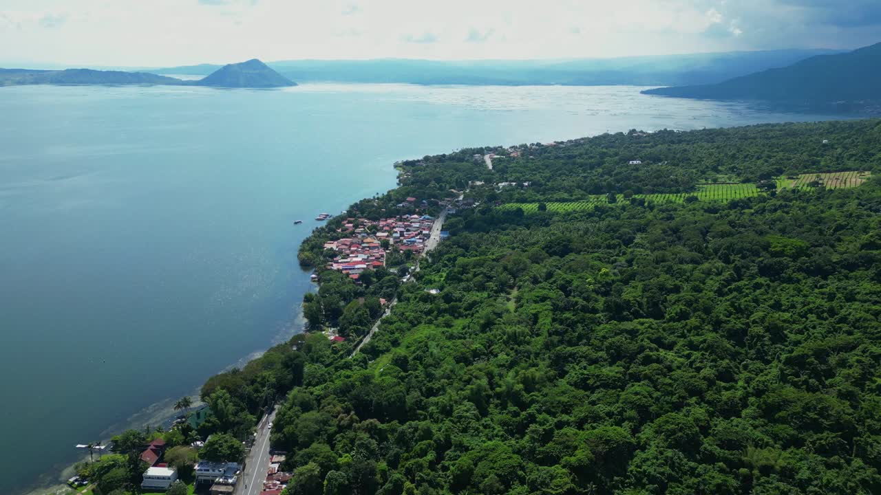 A push-tilt-up aerial of lakeside Talisay town in Batangas revealing Taal Lake and Taal Volcano in the distance, Philippines