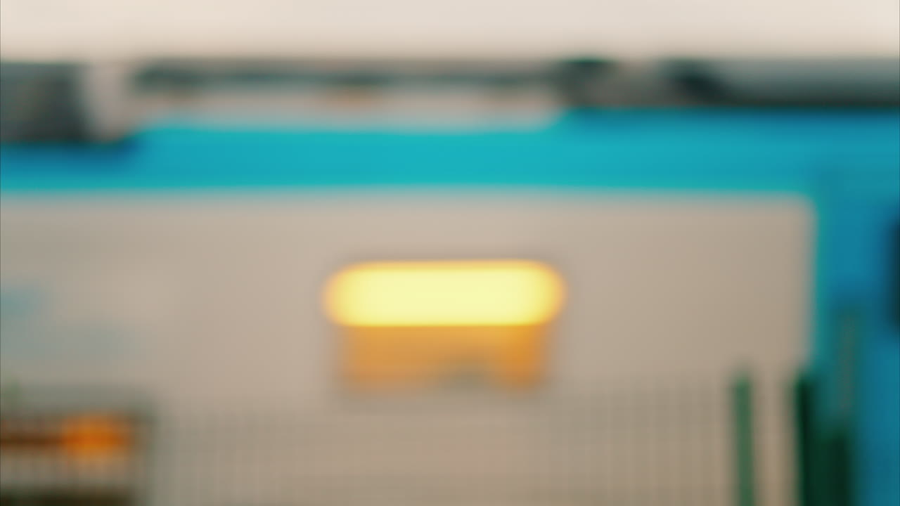 Blurred view of a white and blue train passing by in the evening