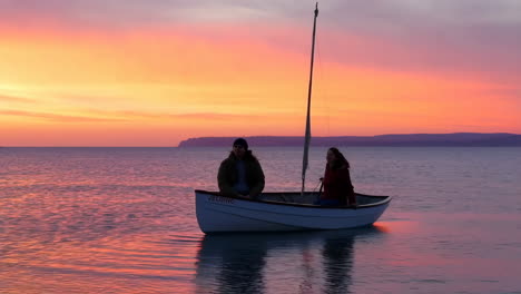 Couple in a small boat on a lake at sunset