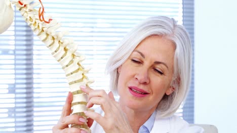 retrato de una doctora que sostiene un modelo de columna vertebral