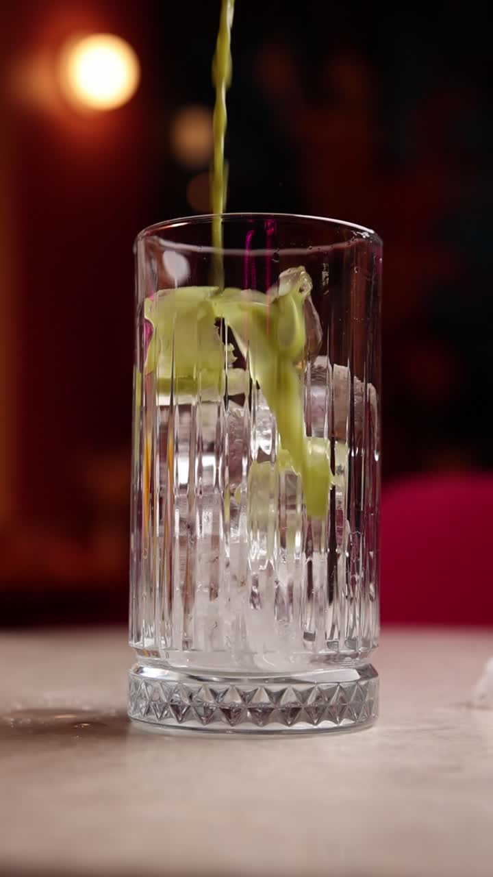 vertiendo bebida verde en un vaso con hielo