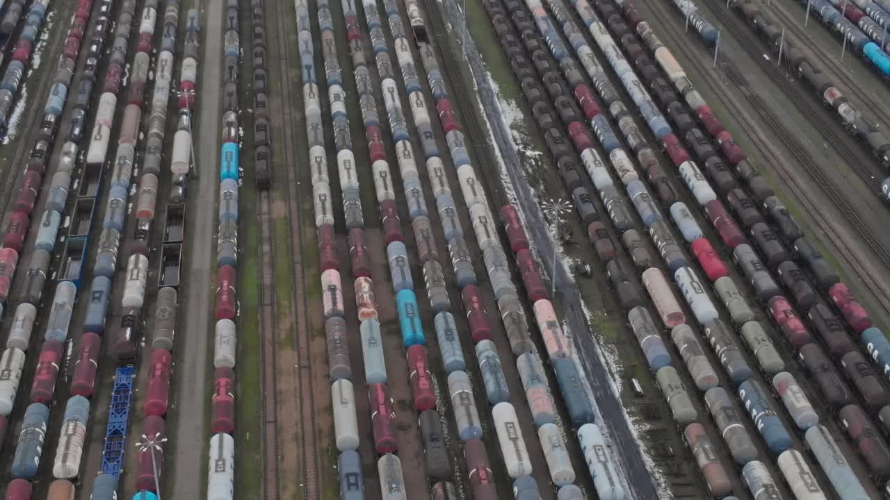 Viele Eisenbahnwaggons stehen an einem bewölkten Tag auf einem Rangierbahnhof aufgereiht.