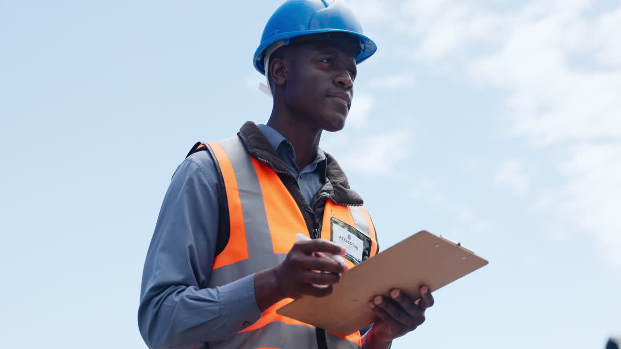 African American Engineer in Hard Hat Writing on Clipboard Outdoors