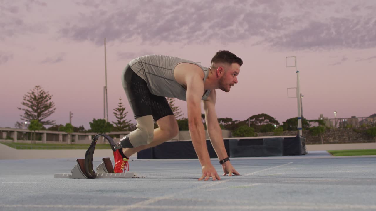 러닝 블레이드 를 가진 백인 장애인 남성 운동 선수 가 달리기 를 시작 할 준비 를 하고 있다