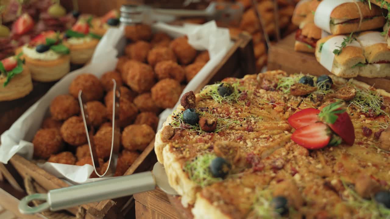 Traveling close-up shot showing a cheese tart topped with fresh strawberries, and a basket filled with meatballs