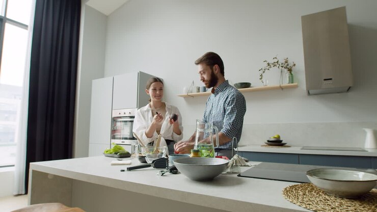 Giovane coppia allegra che prepara insieme l'insalata in una cucina moderna