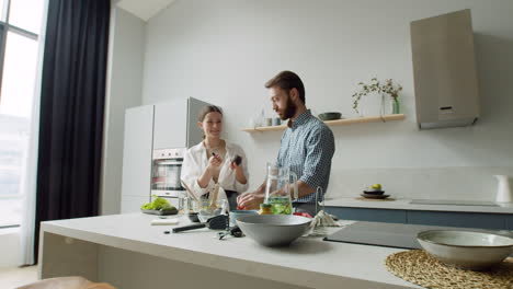 fröhliches junges paar, das gemeinsam salat in einer modernen küche zubereitet