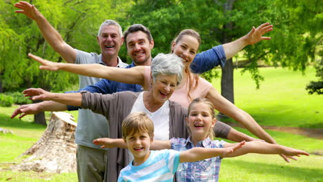 Multi-generation-family-posing-and-smiling-at-camera-in-a-park